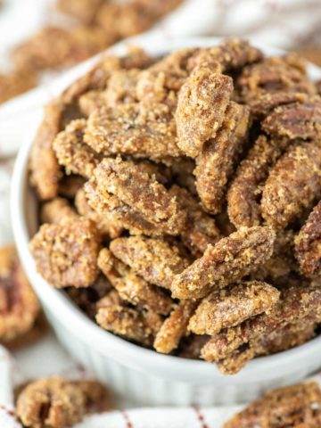 close-up of candied pecans on white ramekin on dish towel
