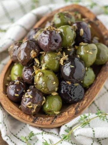 marinated olives in wood bowl on dish towel