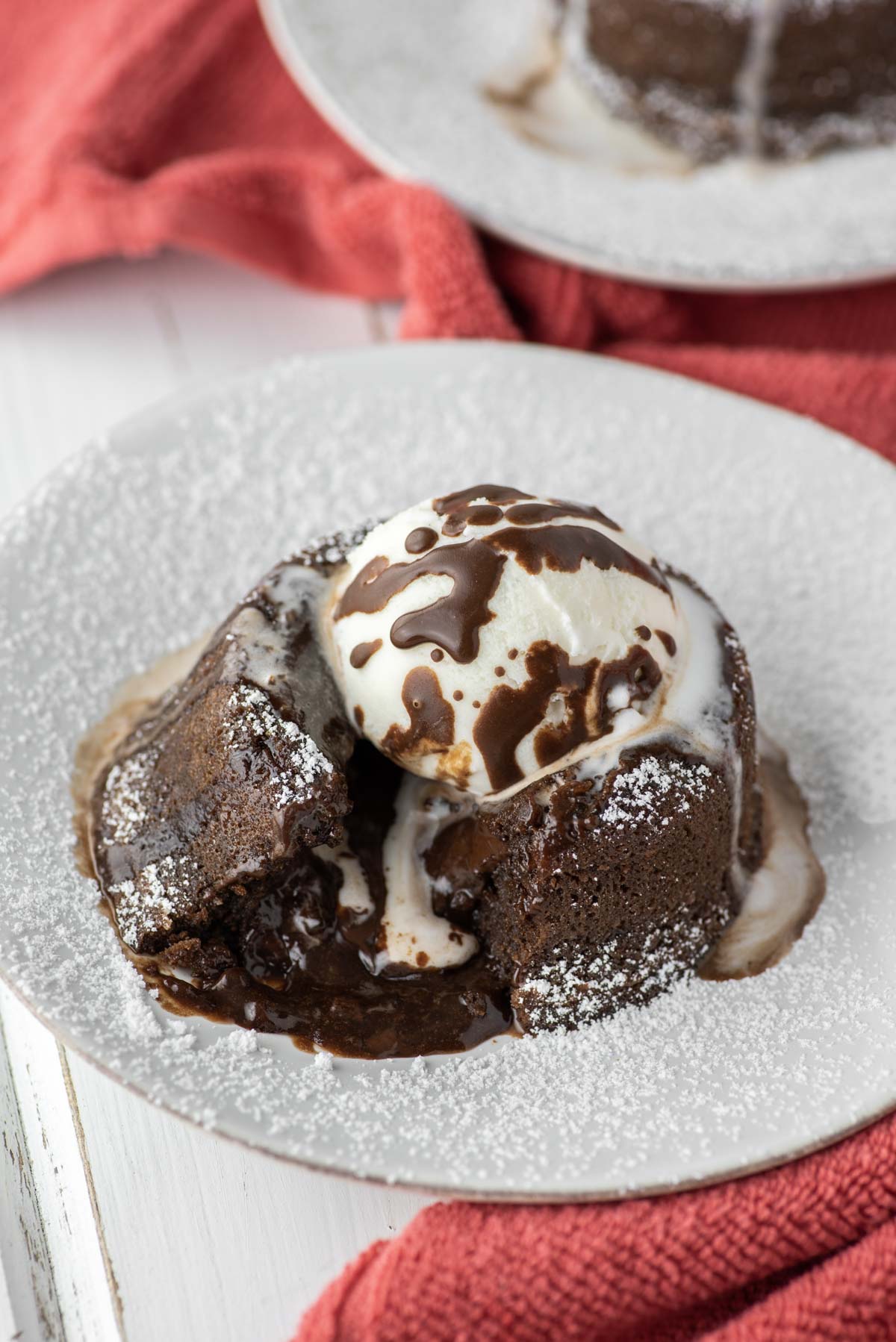 chocolate lava cake with vanilla ice cream on white plate with chocolate oozing out