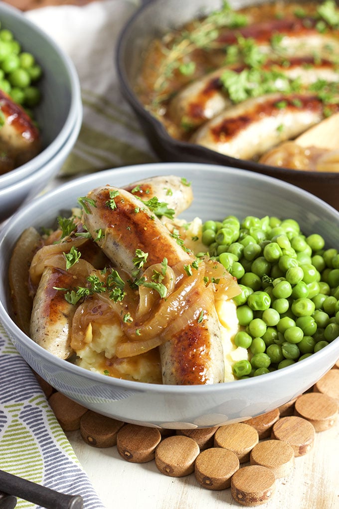 bangers and mash with green peas in grey bowl
