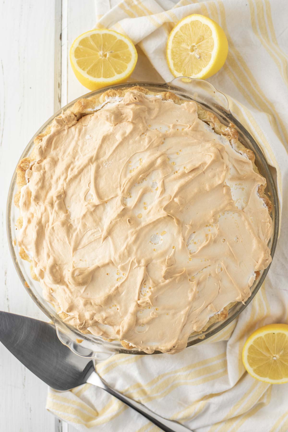 overhead shot of lemon meringue pie in glass pie dish on white background
