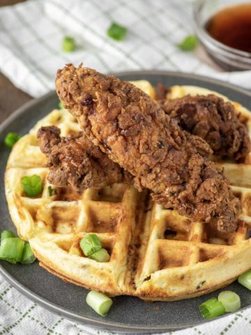 two pieces of fried chicken on bacon cheddar waffle