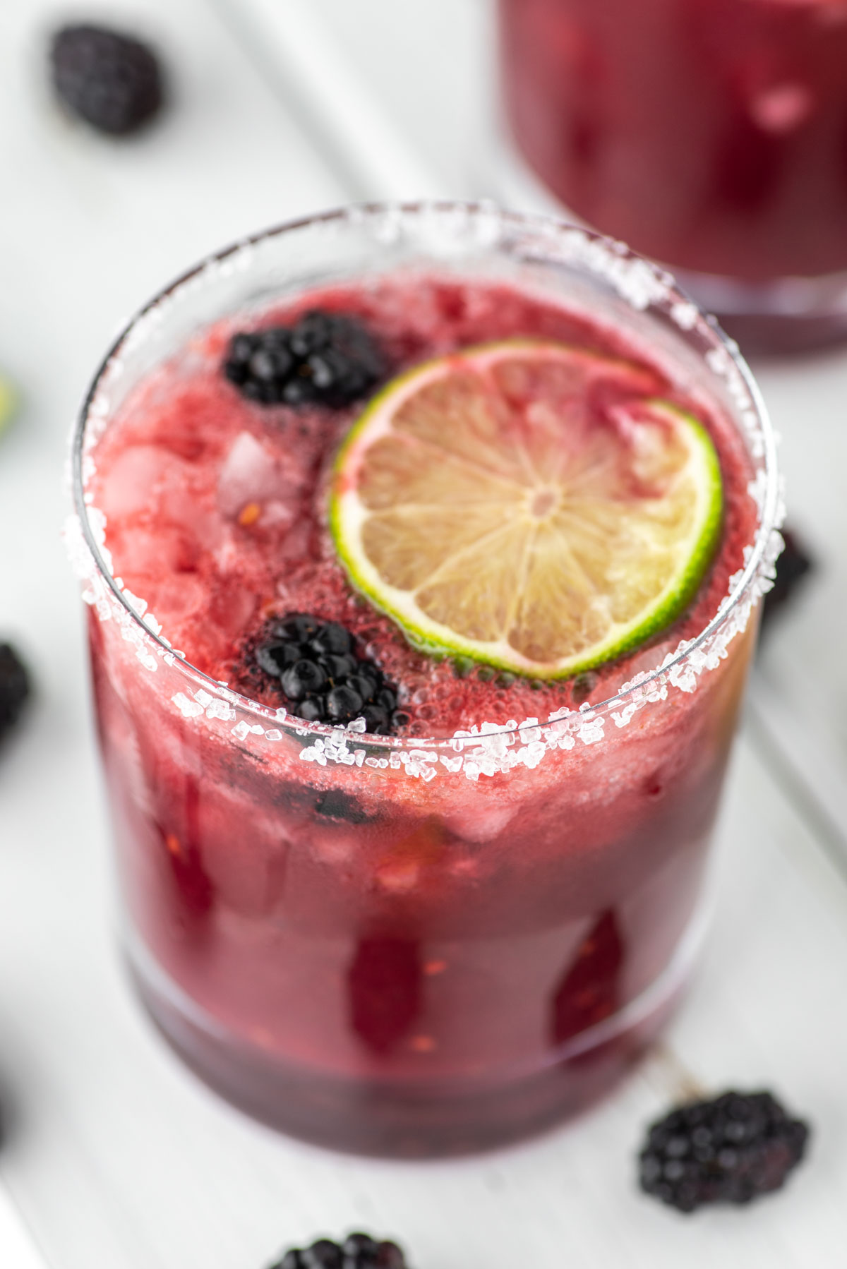 glass of blackberry margarita with lime