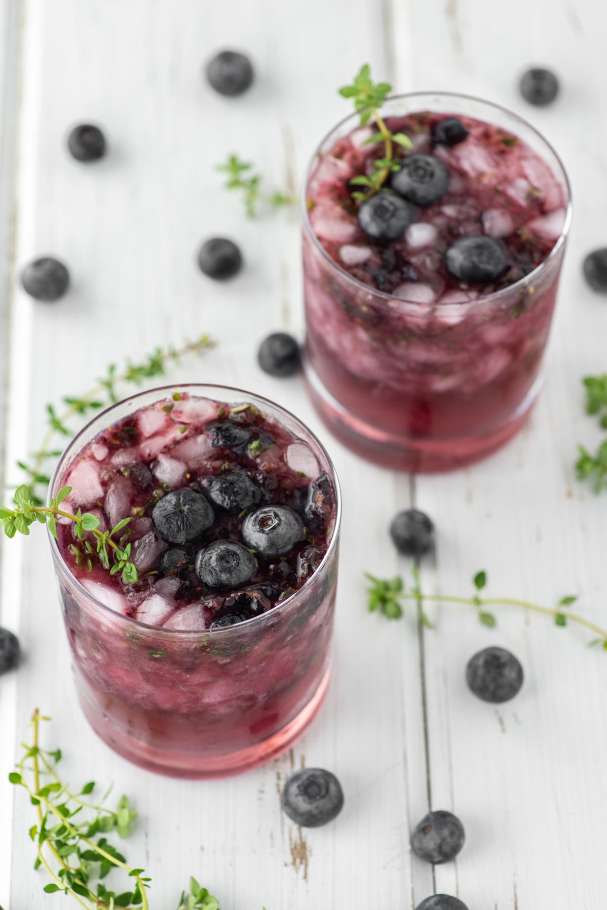 two blueberry cocktails in glasses with fresh blueberries