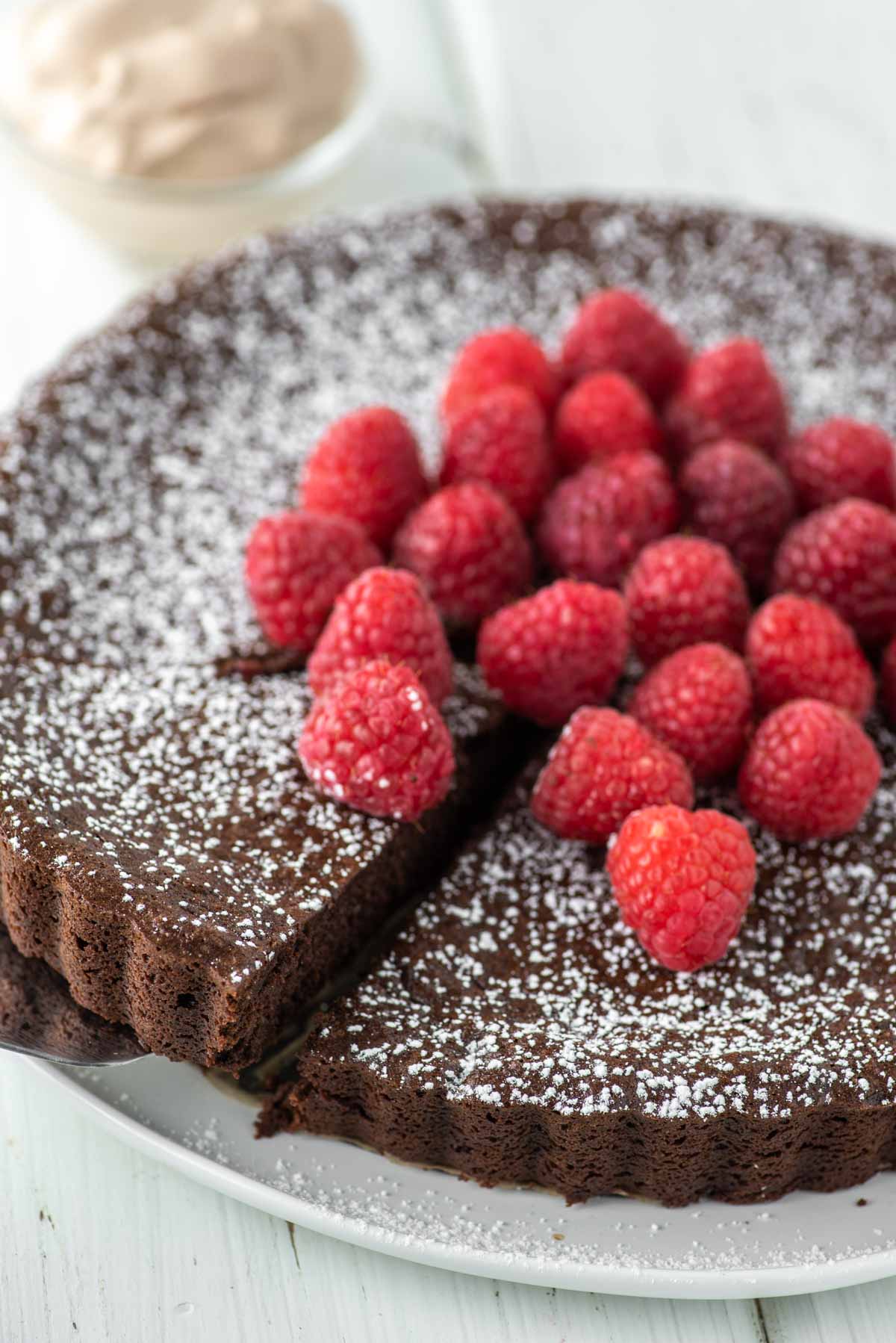 slice of flourless chocolate cake with raspberries being pulled away