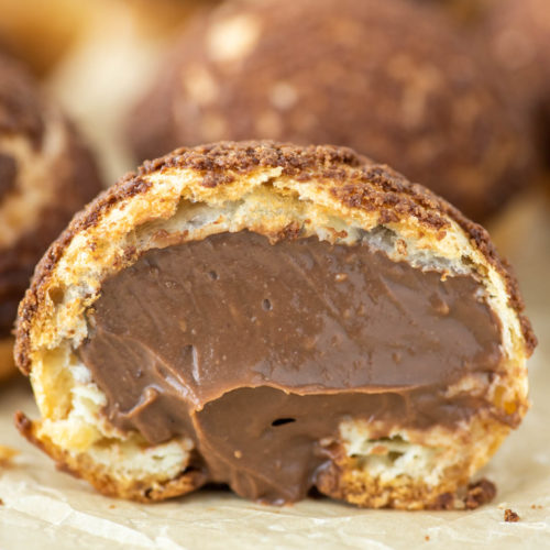 chocolate cream puff cut in half with chocolate pastry cream oozing out