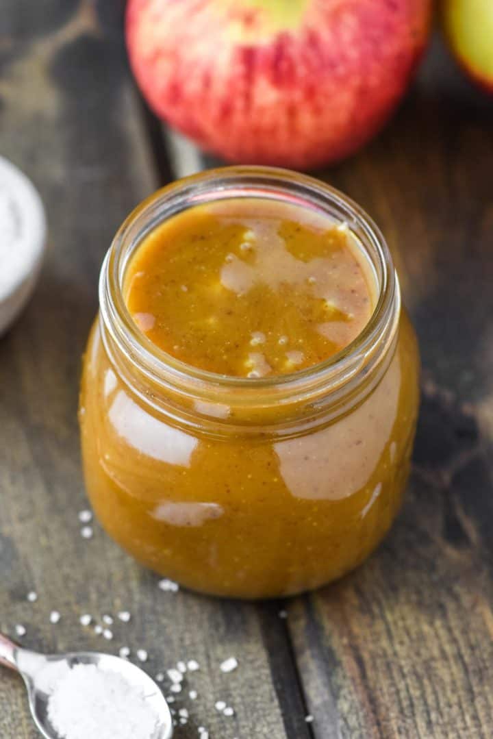 caramel sauce in glass jar with apples in background
