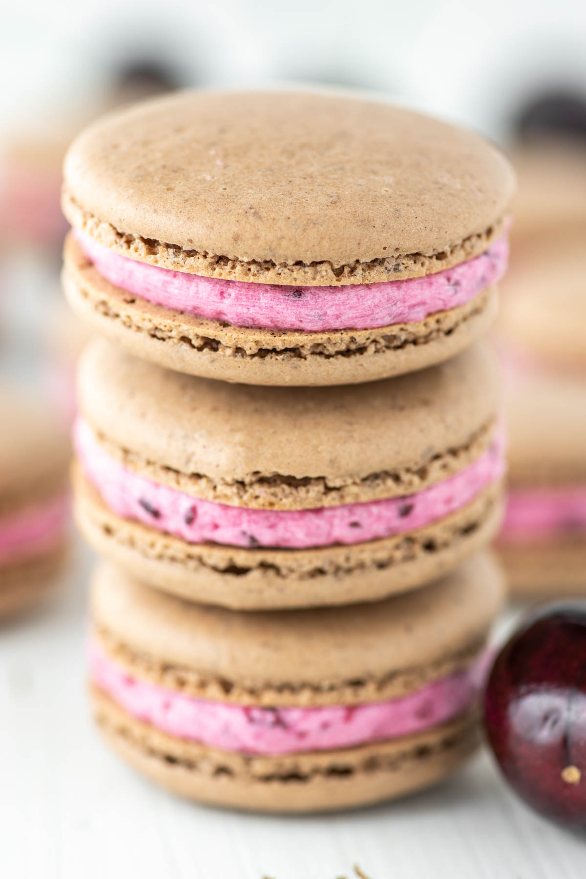 3 stacked cherry macarons with more in the background