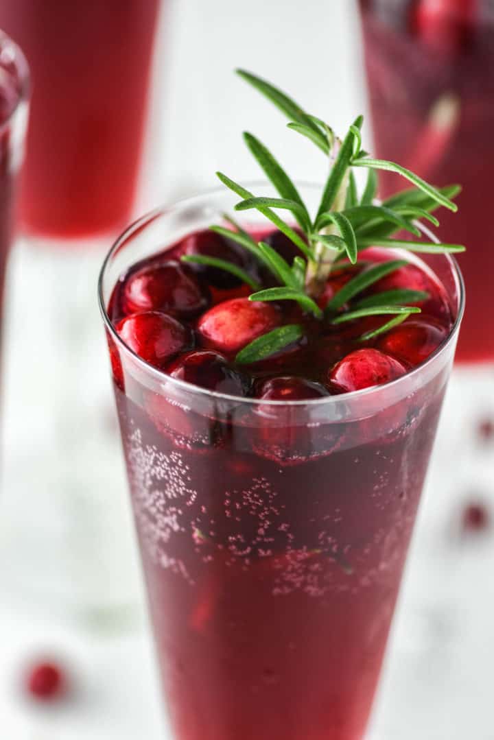 cranberry mimosa with rosemary in champagne glass
