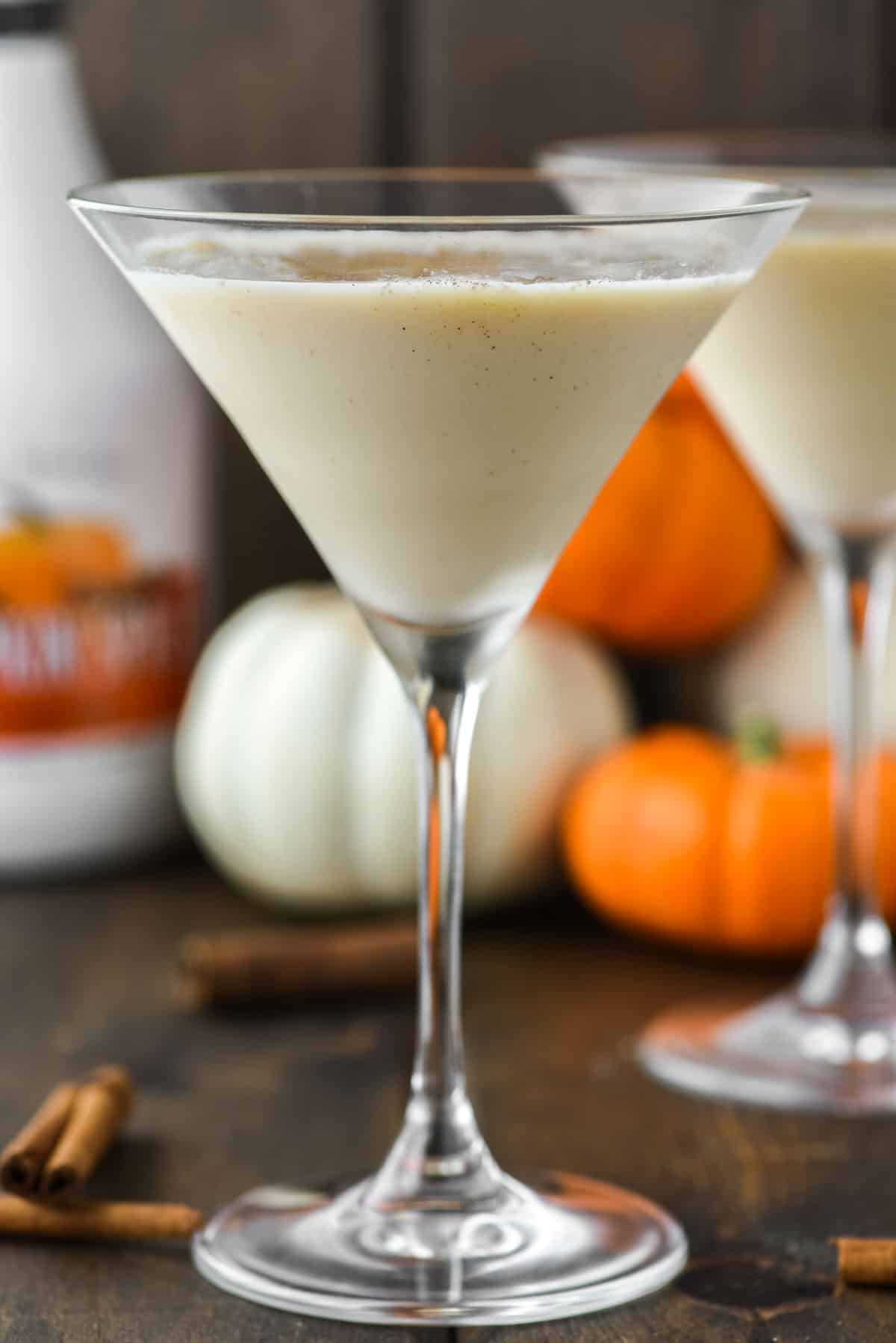 two glasses of pumpkin martini with pumpkins in the background