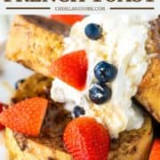 3 slices of sourdough French toast on white plate with whipped cream, strawberries and blueberries