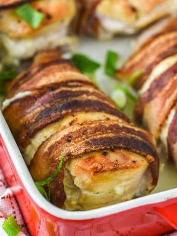 bacon wrapped stuffed chicken in red baking dish