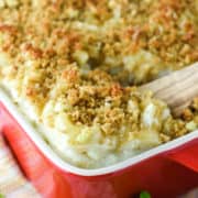 wooden spoon dipped in baking dish with crab mac and cheese