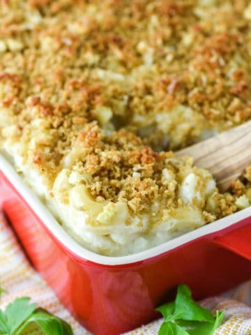 wooden spoon dipped in baking dish with crab mac and cheese
