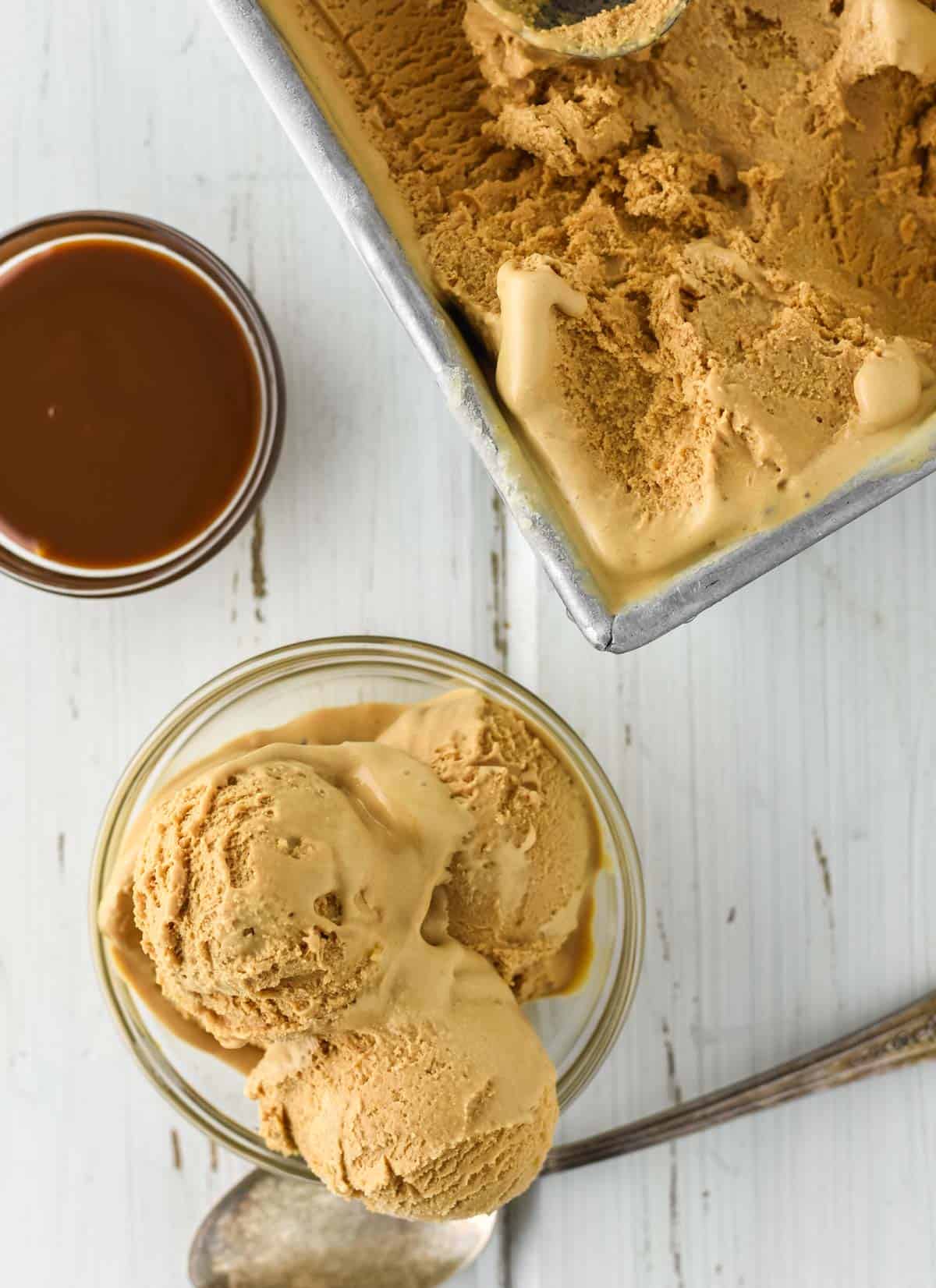 overhead shot of dulce de leche ice cream in glass bowl and tin