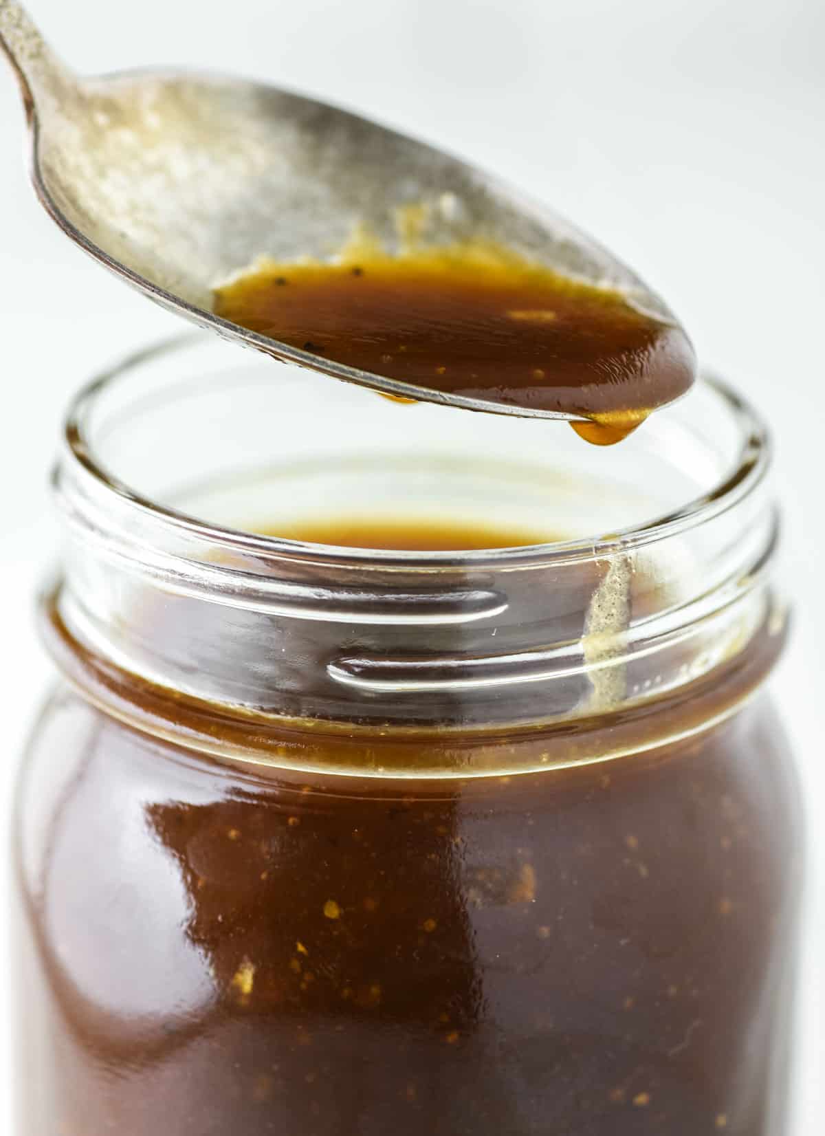 spoon dipped in mason jar with balsamic dressing