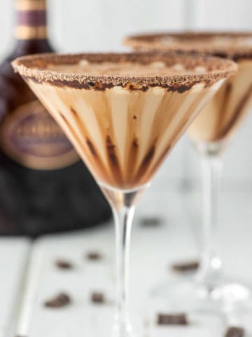 two glasses of Godiva chocolate martinis with Godiva liqueur in the background