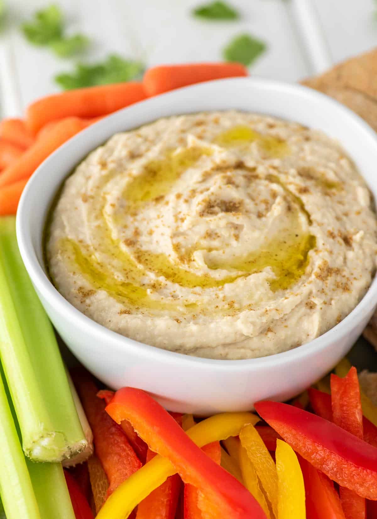 bowl of white bean hummus with carrots, celery and peppers