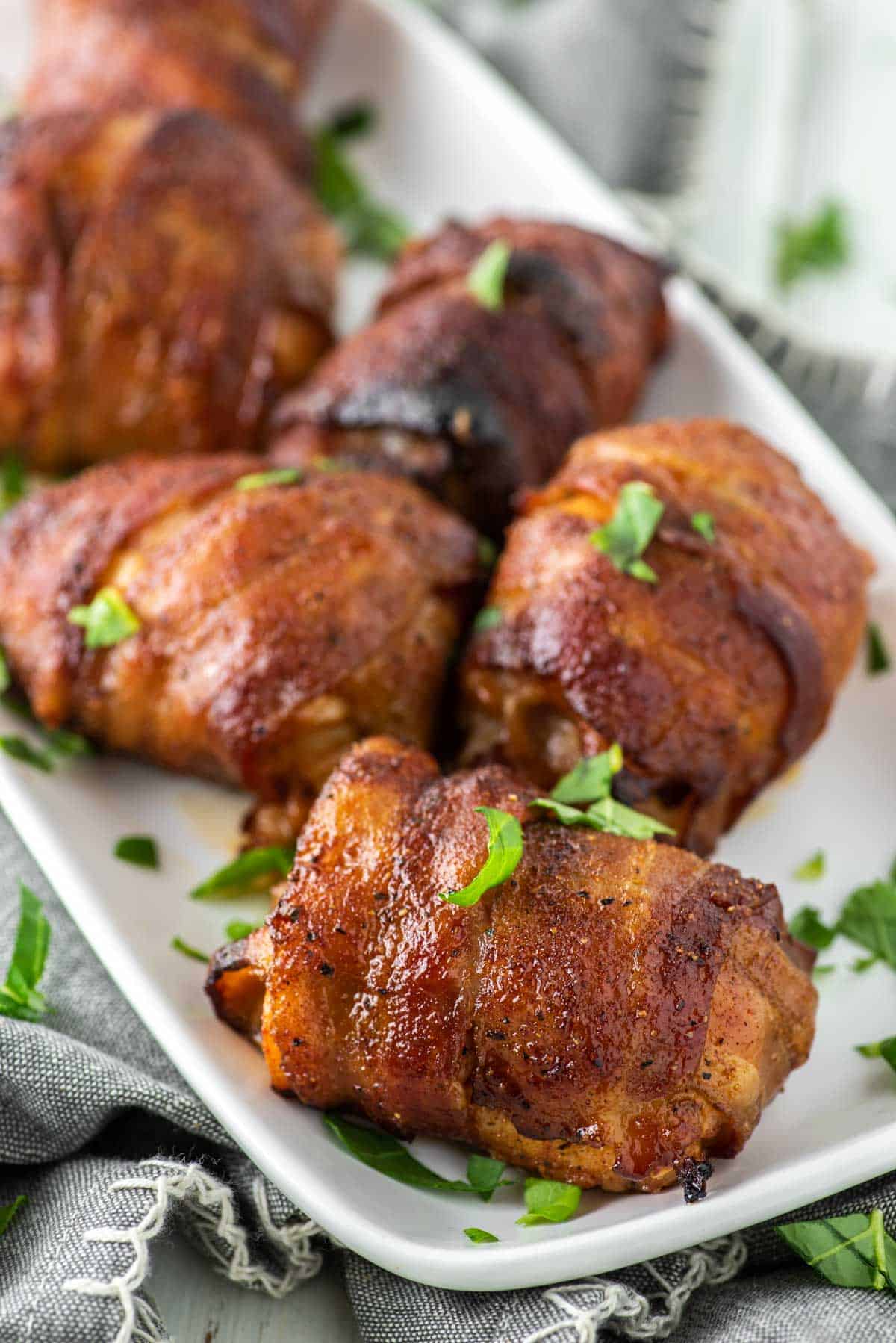 bacon wrapped chicken thighs on white plate