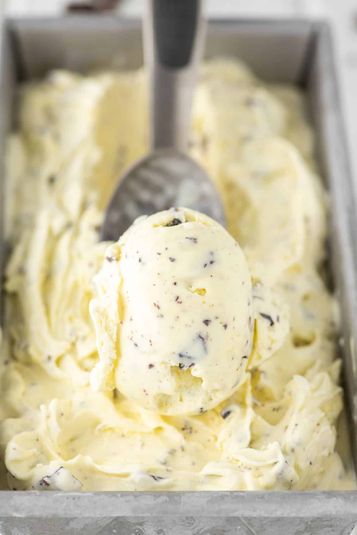 chocolate chip ice cream being scooped out of metal tin