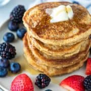 stacked pancakes with butter and fruit on plate