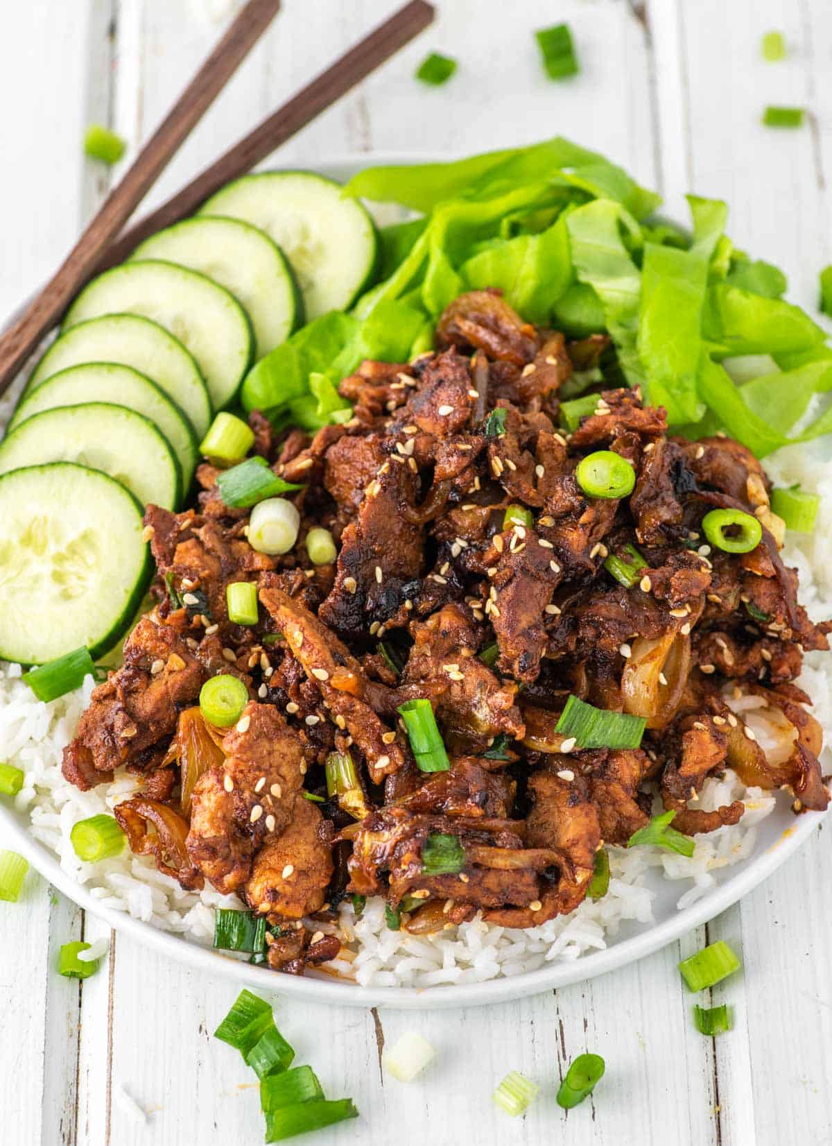 pork bulgogi on top of rice with sliced cucumbers and lettuce