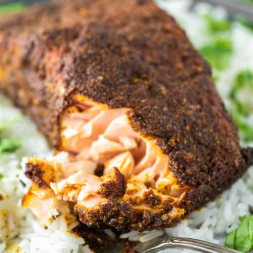 fork cut into tandoori salmon on plate of white rice