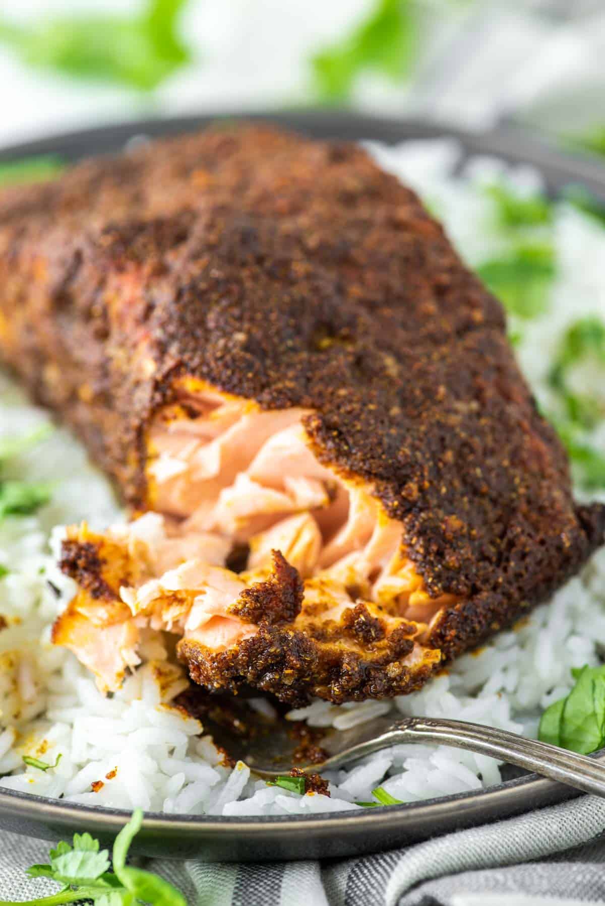 fork cut into tandoori salmon on plate of white rice