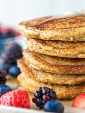 stacked pancakes with oat flour on plate and fruit