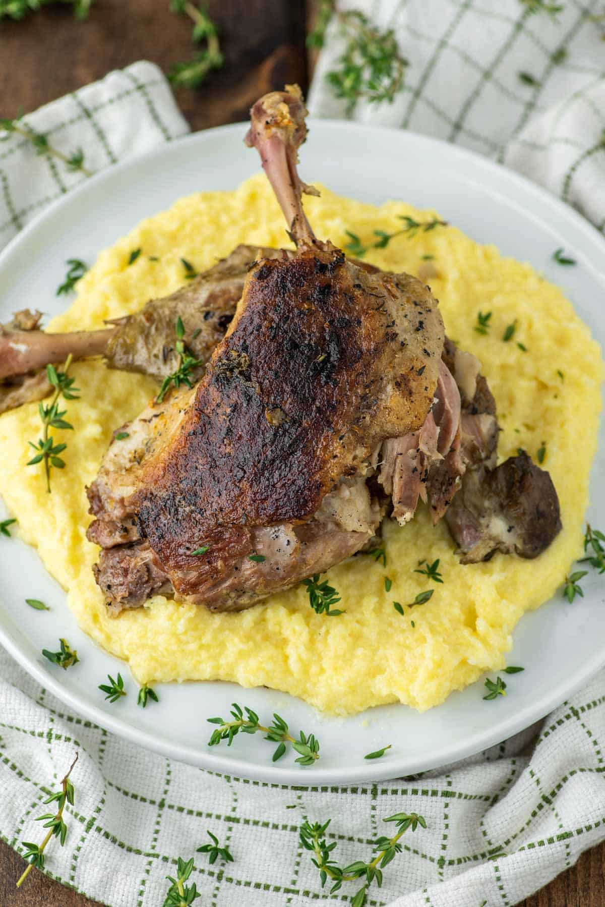 duck confit with polenta on white plate