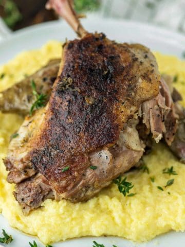 sous vide duck confit with polenta on white plate