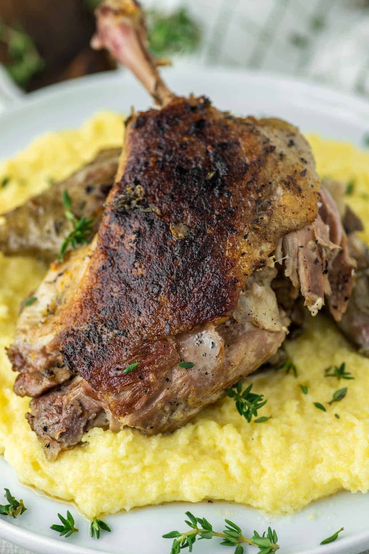 sous vide duck confit with polenta on white plate