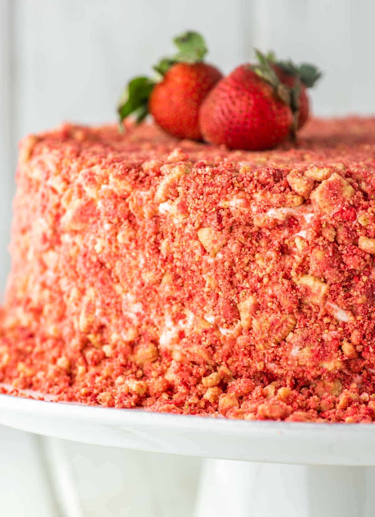 strawberry crunch cake on white cake stand