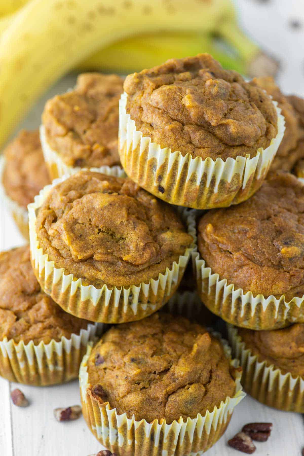 stacked pumpkin banana muffins with bananas in the background