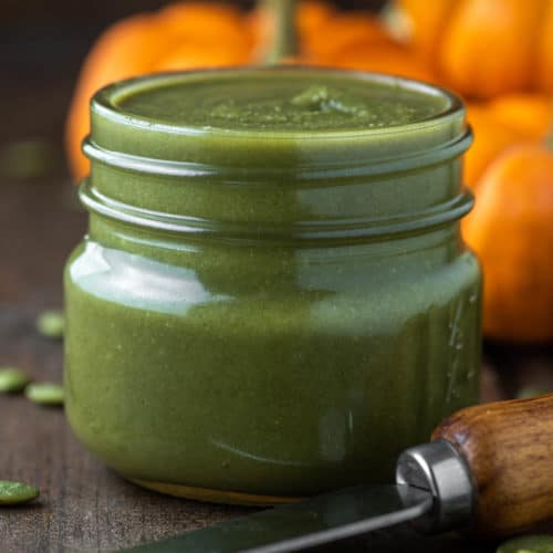 pumpkin seed butter in glass jar with pumpkins in background