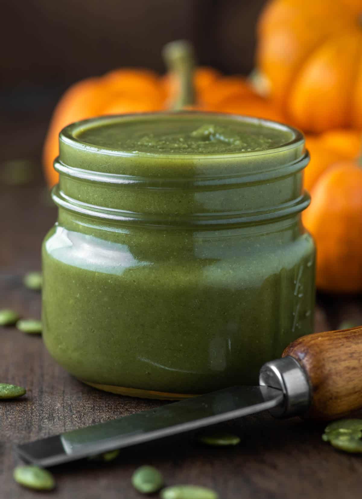 pumpkin seed butter in glass jar with pumpkins in background