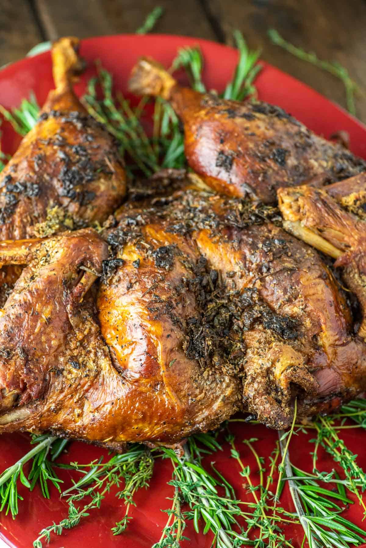 spatchcock smoked turkey on red plate with herbs