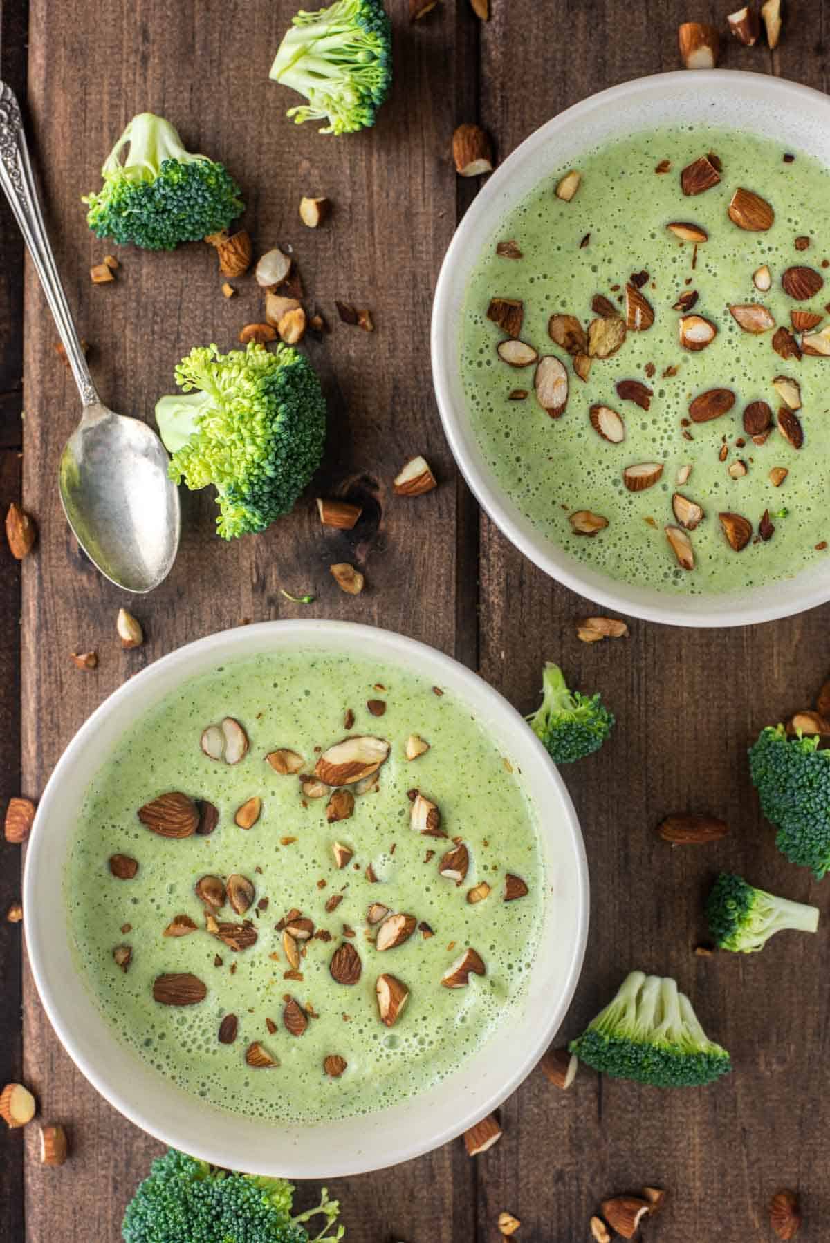overhead shot of two bowls of broccoli almond soup
