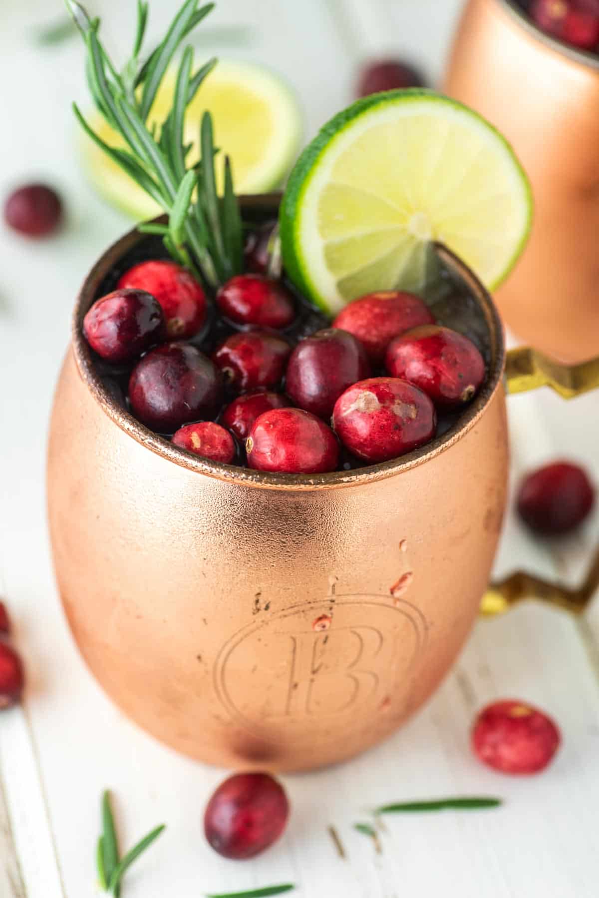 cranberry Moscow Mule with fresh cranberries, rosemary and lime in copper mug