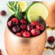 cranberry Moscow Mule with fresh cranberries, rosemary and lime in copper mug