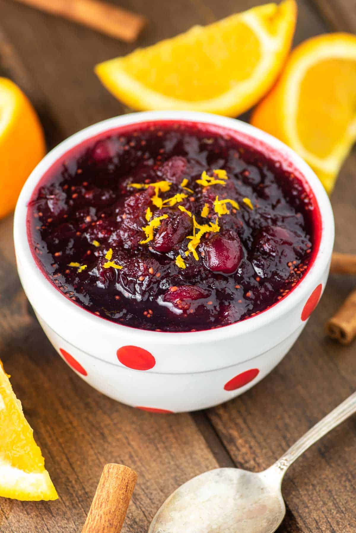 Instant Pot cranberry sauce in white bowl with oranges in background