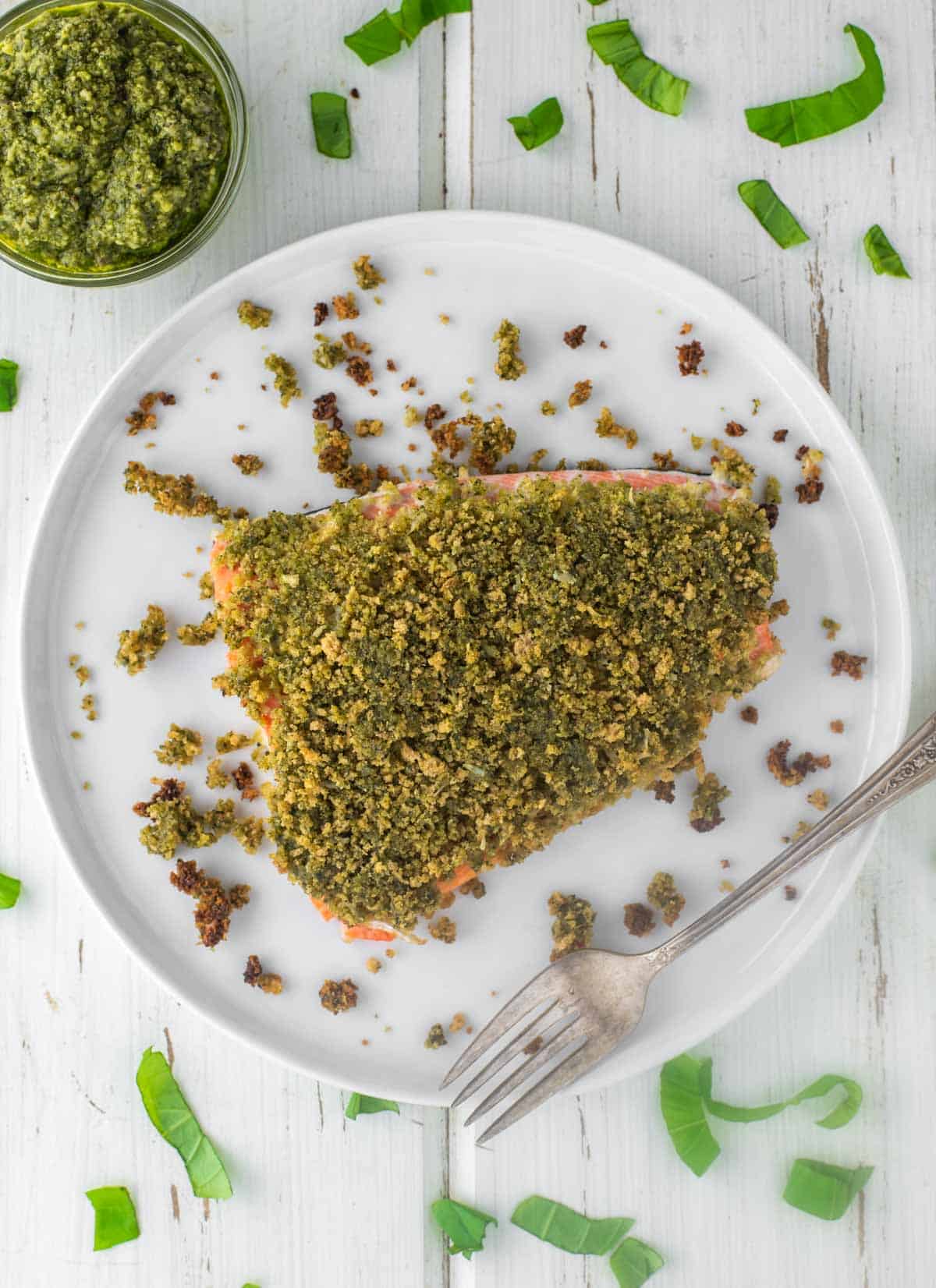 overhead shot of pesto crusted salmon on white plate