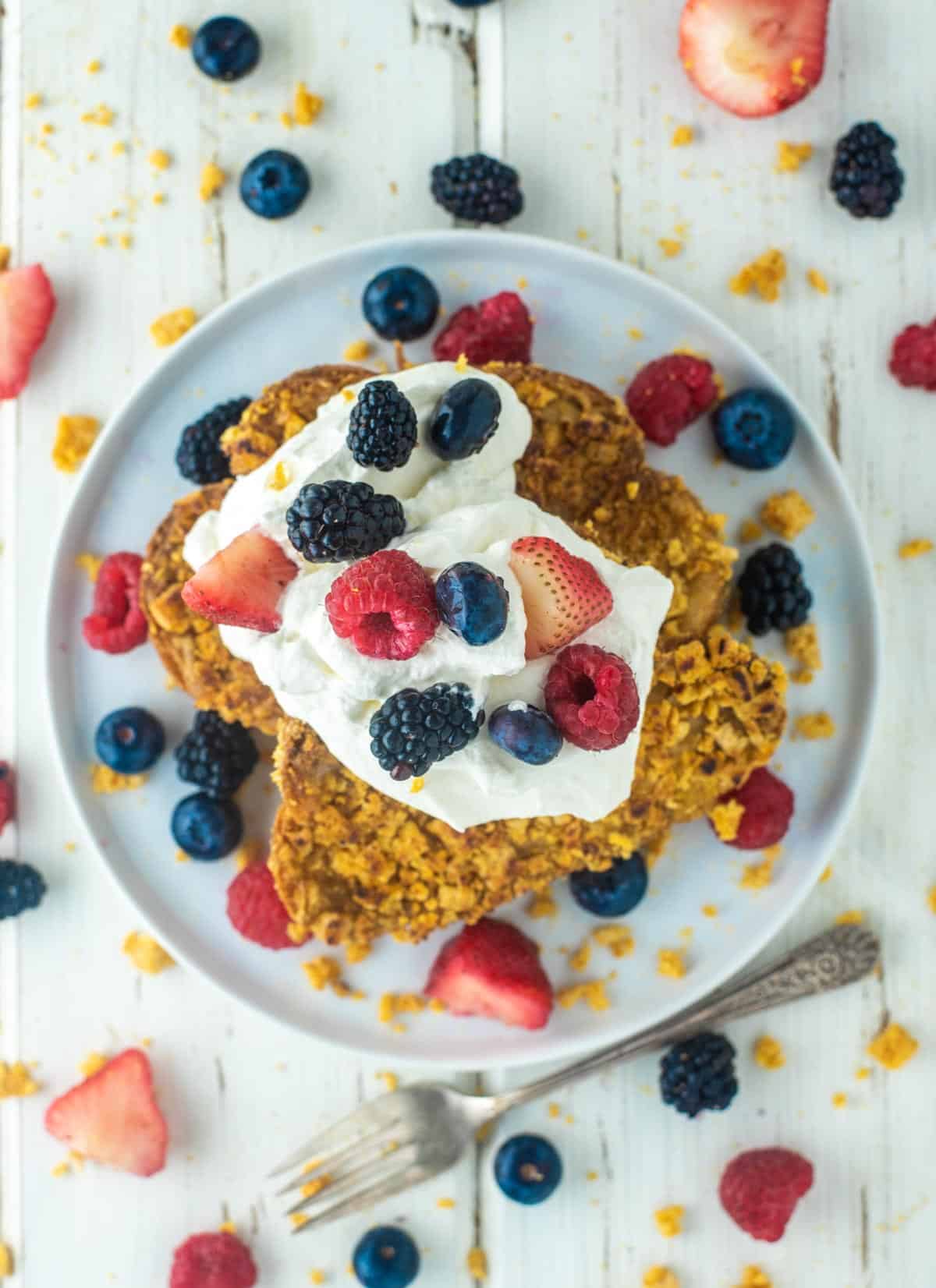 overhead shot of Captain Crunch French toast on plate with whipped cream and berries
