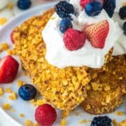 two slices of Captain Crunch French toast on plate with whipped cream and berries