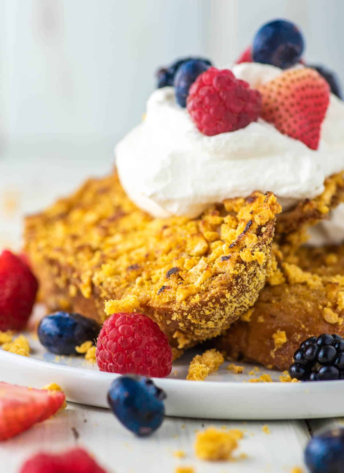 two slices of Cap'n Crunch French toast on plate with whipped cream and berries