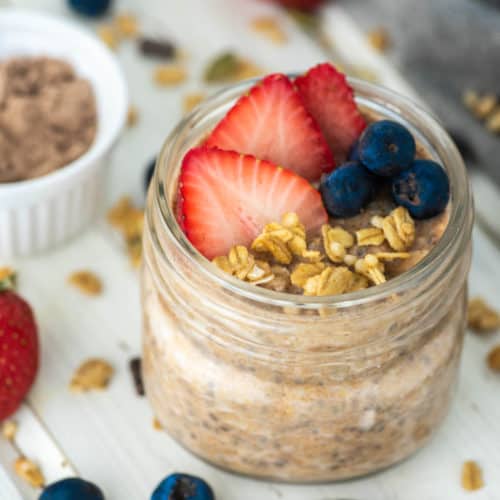 fruit and granola on top of some protein overnight oats in glass jar