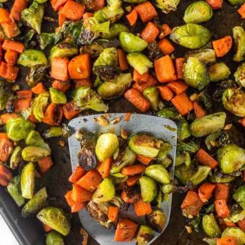overhead shot of spatula lifting out Brussels sprouts and carrots from pan