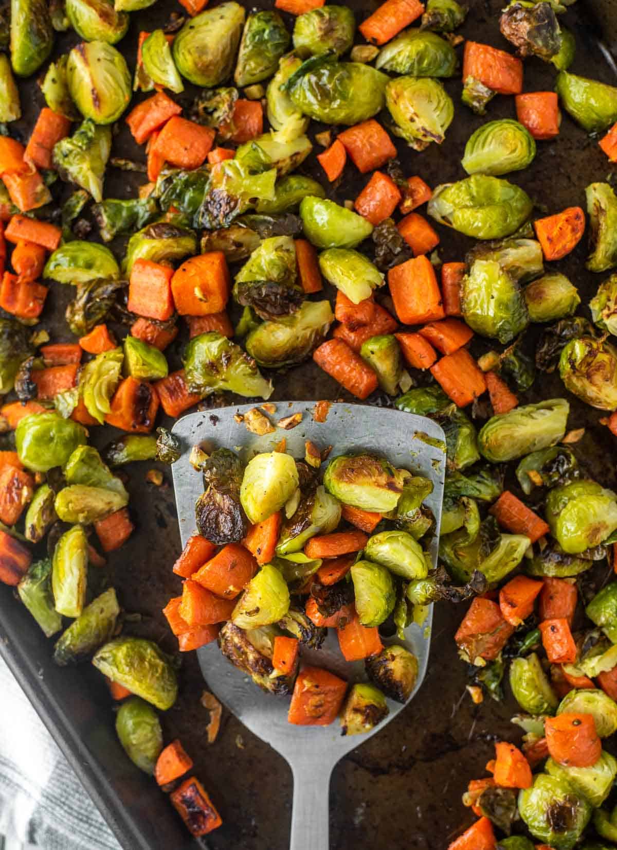 overhead shot of spatula lifting out Brussels sprouts and carrots from pan