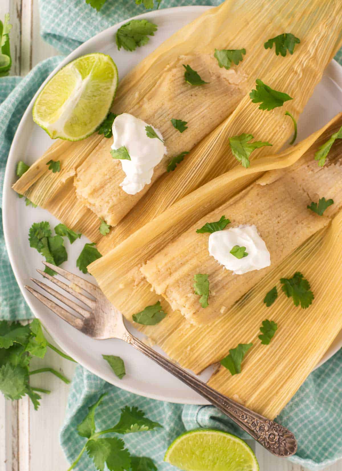 overhead shot of green chile chicken tamales on white plate with fork