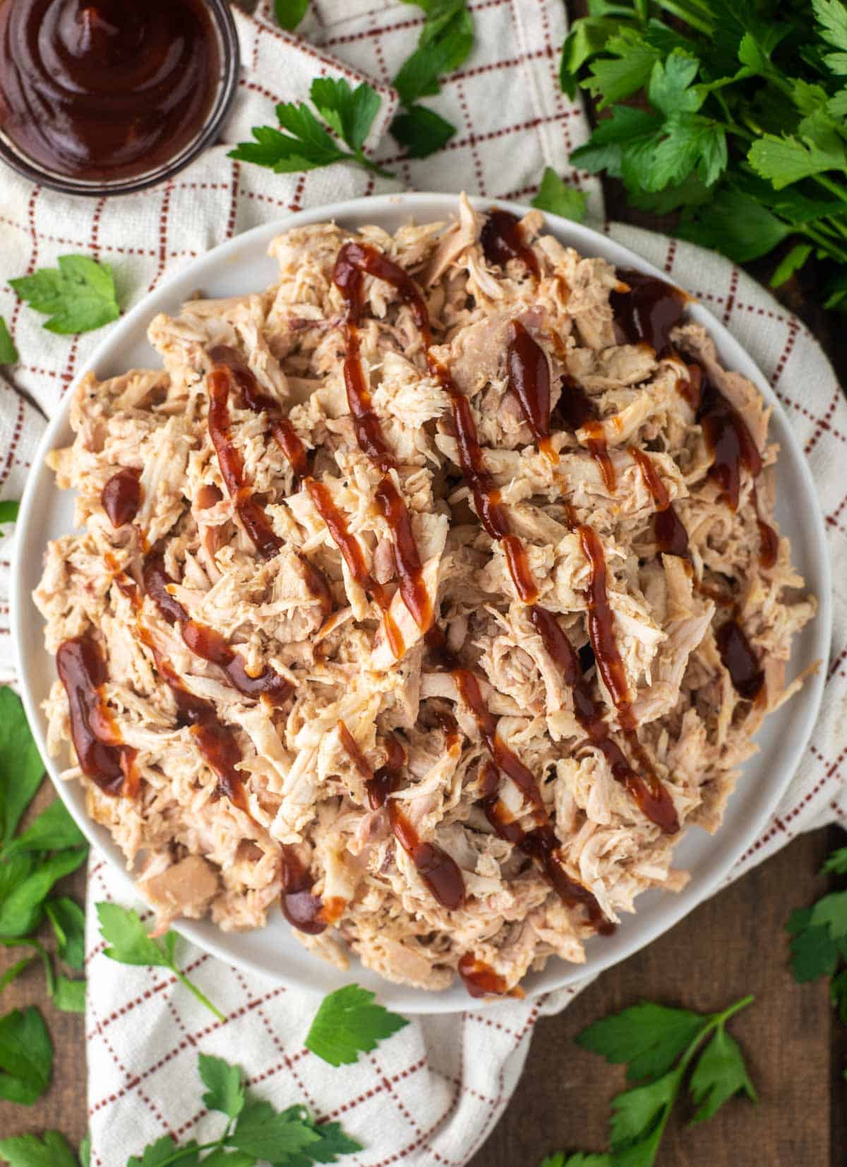 overhead shot of pulled chicken on white plate with BBQ sauce
